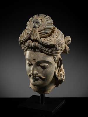 Lot 248 - A LARGE SCHIST HEAD OF A BODHISATTVA WITH A ‘KĪRTIMUKHA’ TURBAN, GANDHARA, 4TH–5TH CENTURY, FORMERLY IN THE COLLECTION OF BEGUM BAKHT ZEBA