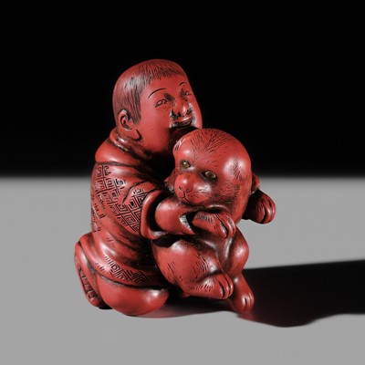 JUGYOKU: A RARE TSUISHU (CARVED RED LACQUER) NETSUKE OF A BOY PLAYING WITH A PUPPY