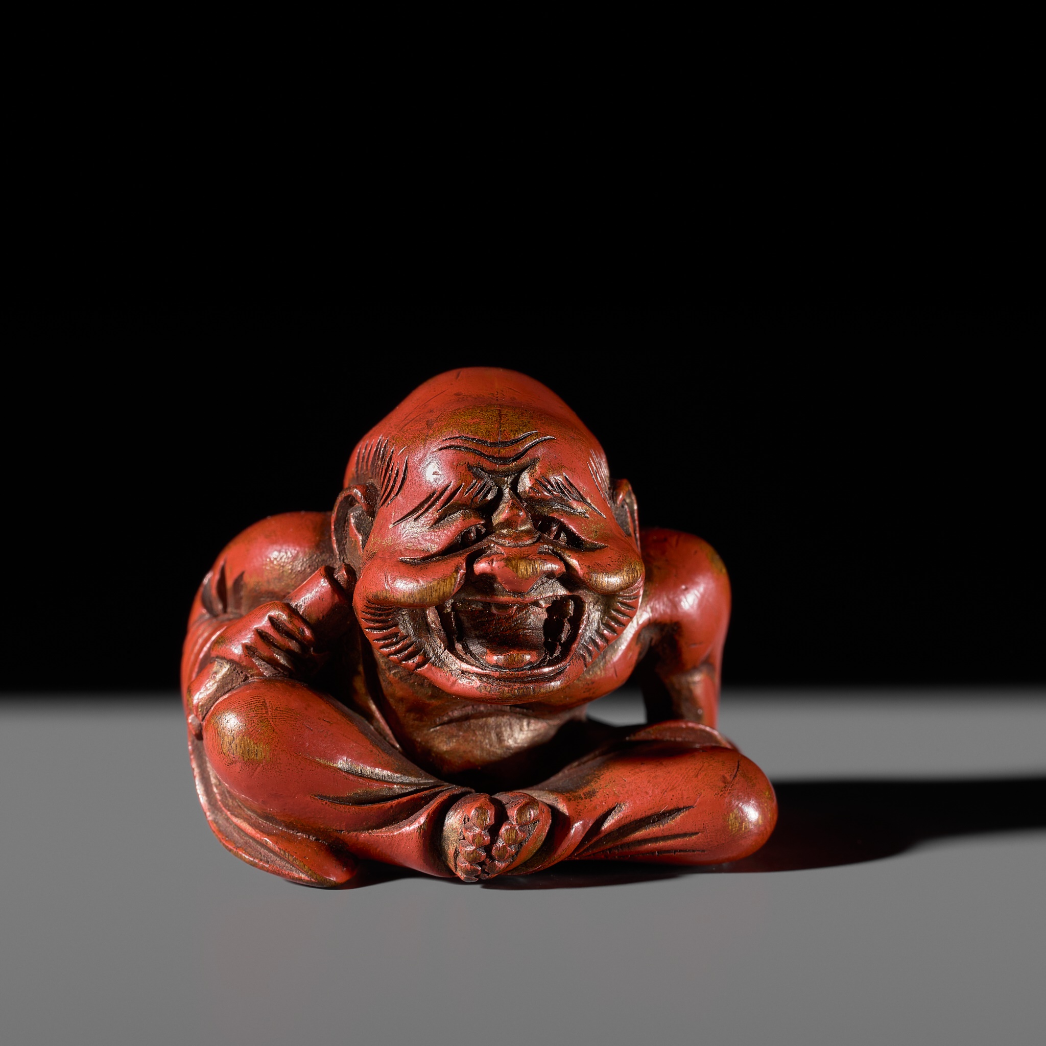 Lot 65 - A RARE RED LACQUER NETSUKE OF A LAUGHING