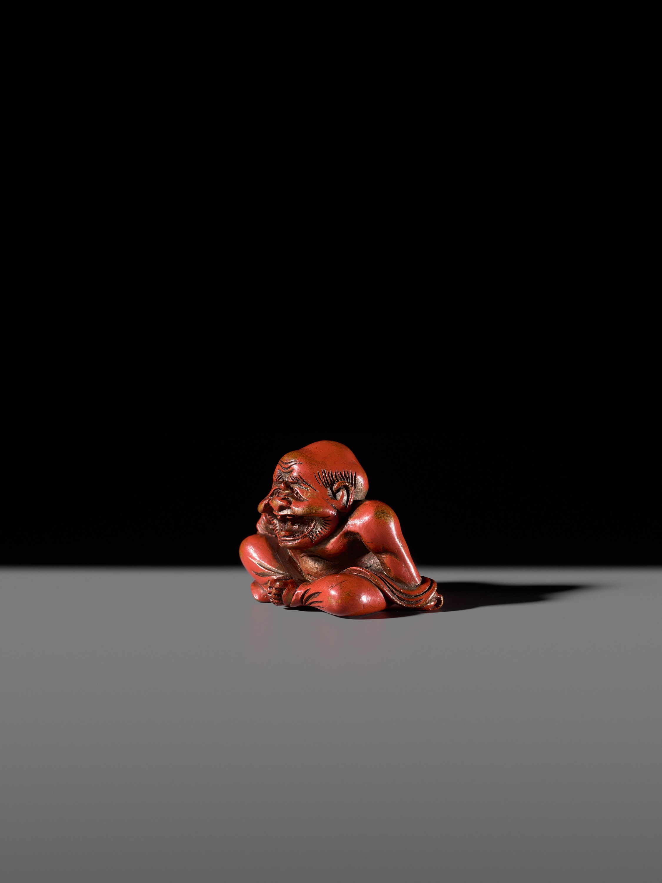 Lot 65 - A RARE RED LACQUER NETSUKE OF A LAUGHING