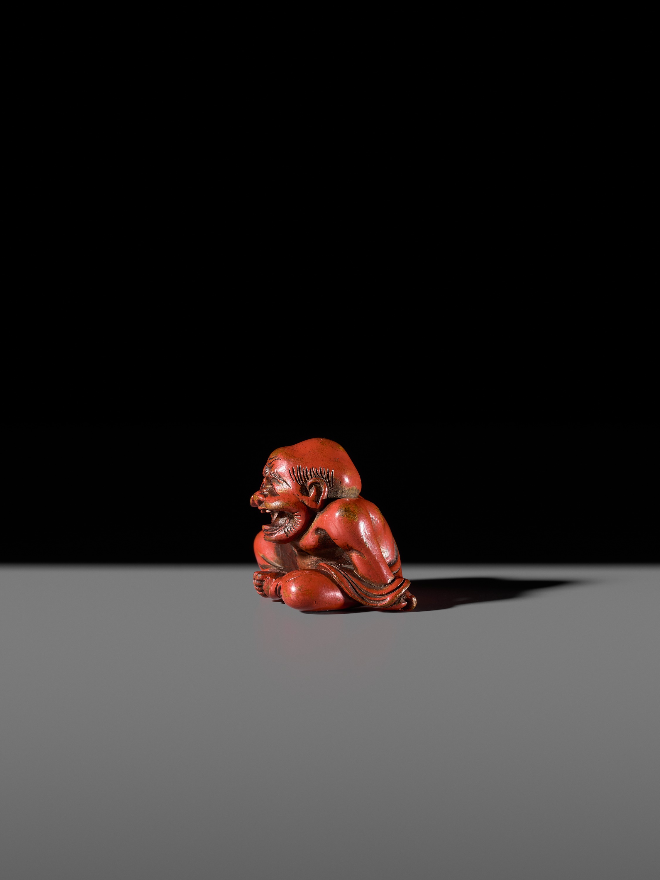 Lot 65 - A RARE RED LACQUER NETSUKE OF A LAUGHING
