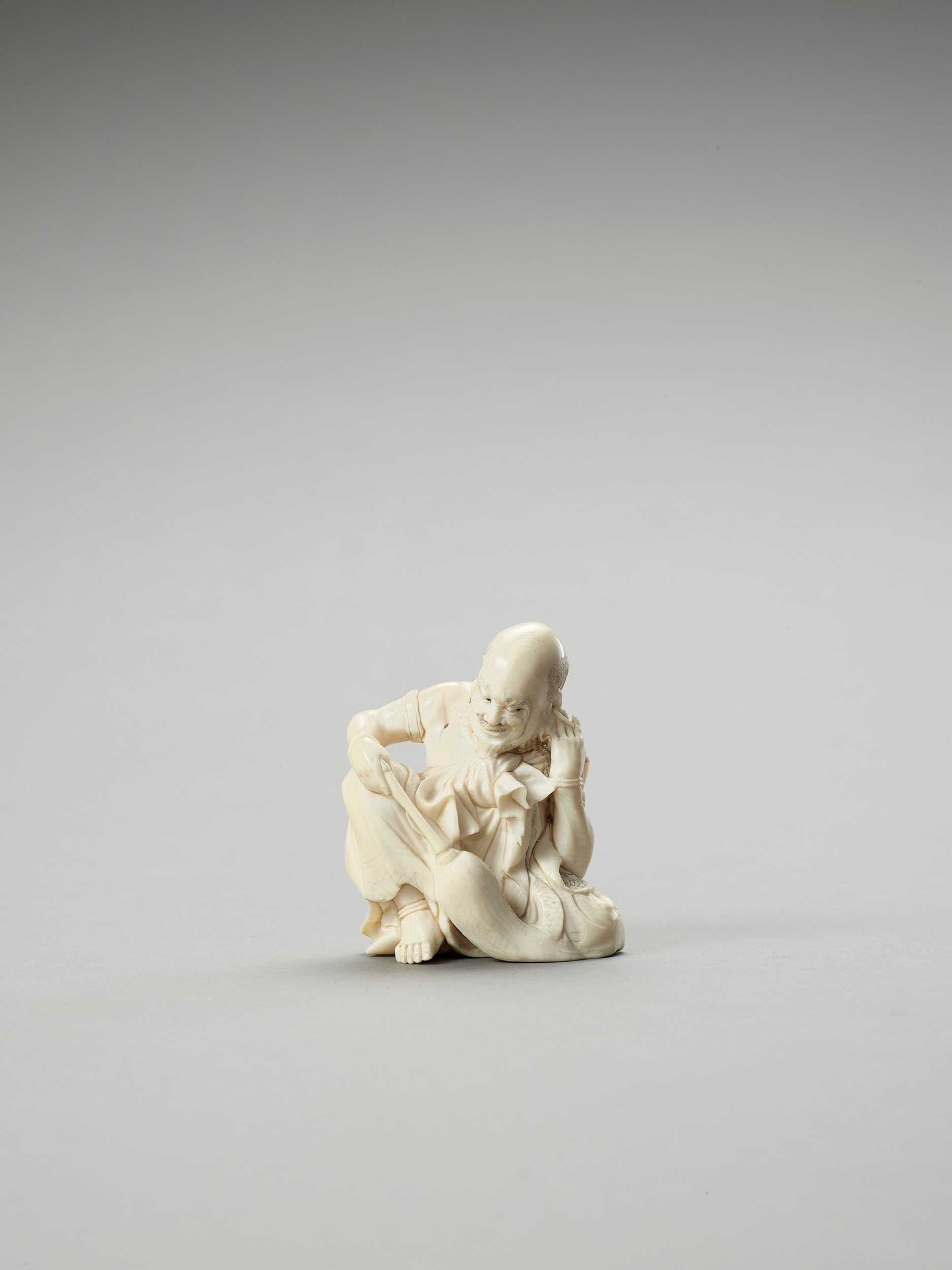 Lot 241 - AN IVORY OKIMONO OF A RAKAN CLEANING HIS EAR