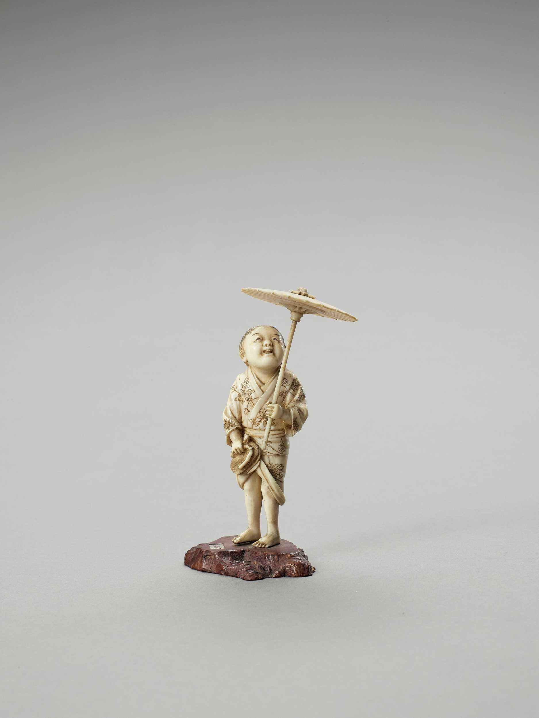 Lot 158 - AN IVORY OKIMONO OF A BOY WITH PARASOL