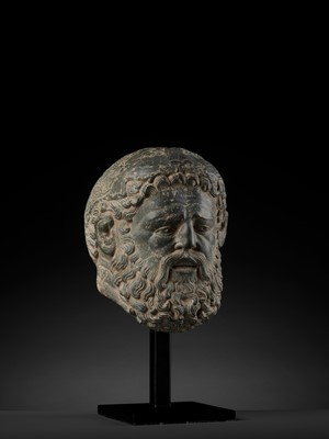 Lot 695 - A LIFE-SIZED HEAVY GRAY SCHIST HEAD OF HERACLES, GANDHARA, 4TH-5TH CENTURY
