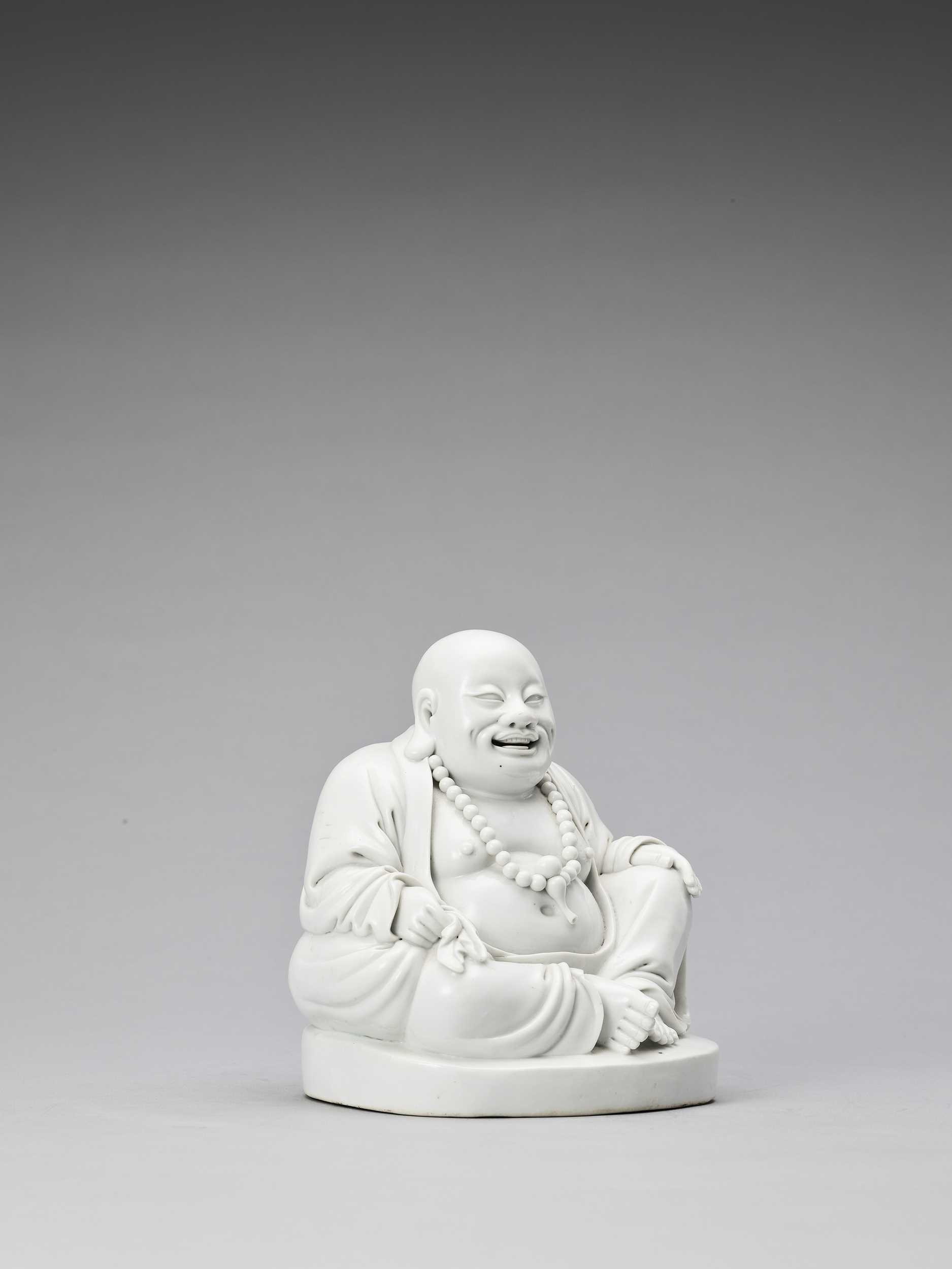 Lot 848 - A WHITE GLAZED DEHUA PORCELAIN FIGURE OF BUDAI, QING