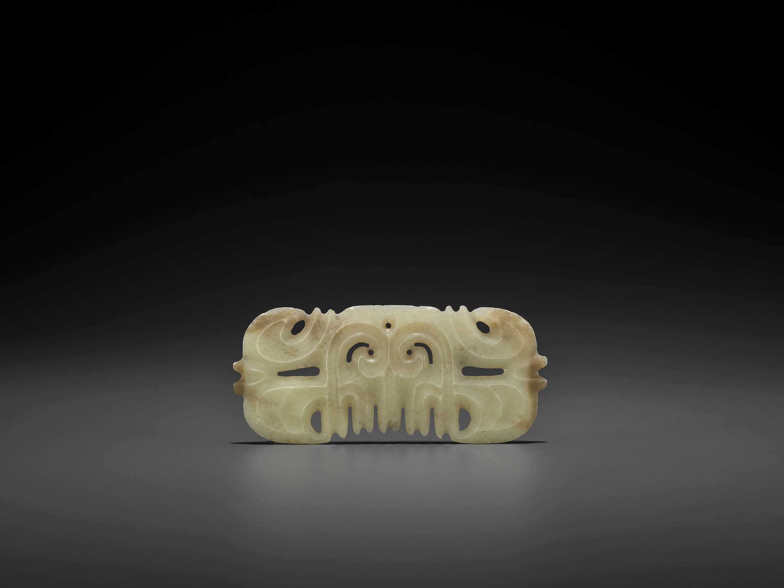Lot 153 - A LIGHT YELLOW JADE ‘TOOTHED’ ORNAMENT WITH MASK MOTIF