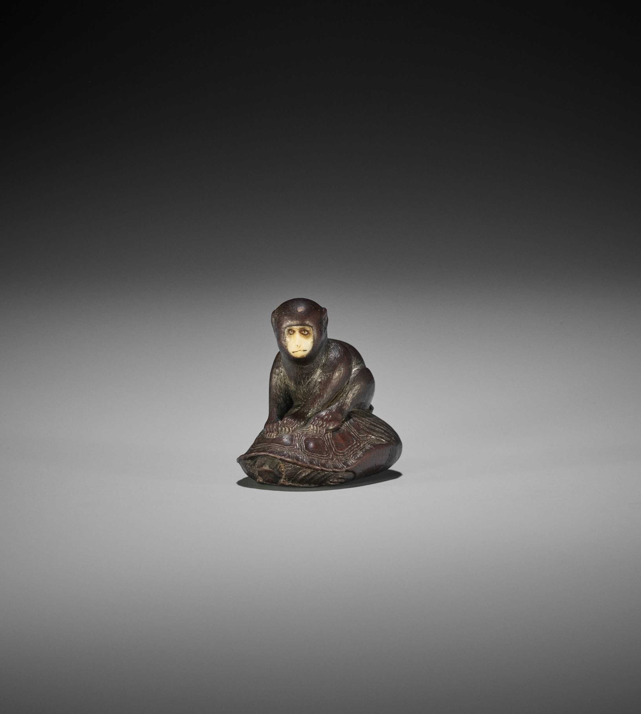 Lot 212 - SO: A FINE AND CHARMING TOKYO SCHOOL WOOD NETSUKE OF A MONKEY SEATED ON A MINOGAME