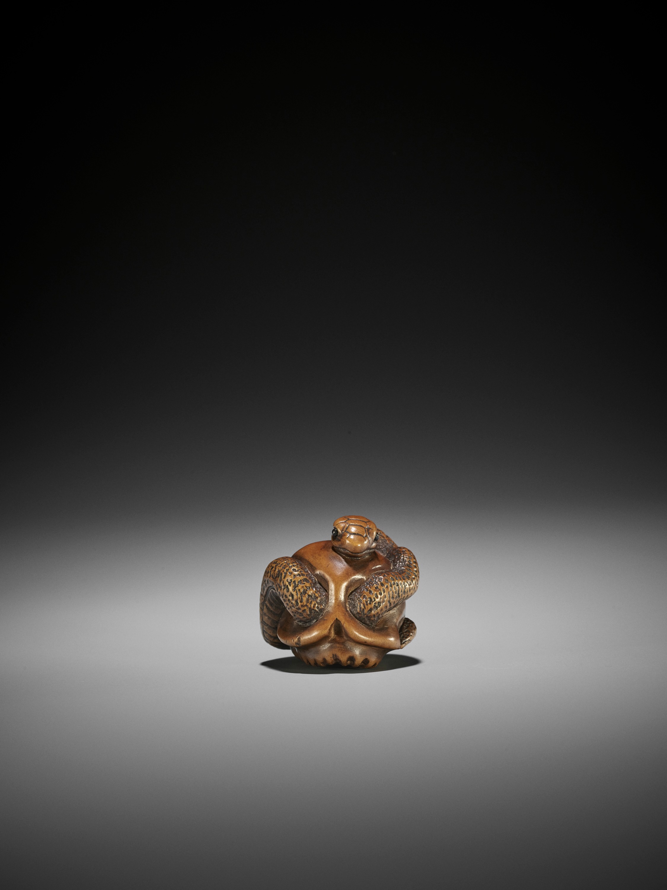 Lot 99 - MASAMITSU: A WOOD NETSUKE OF SNAKE AND SKULL