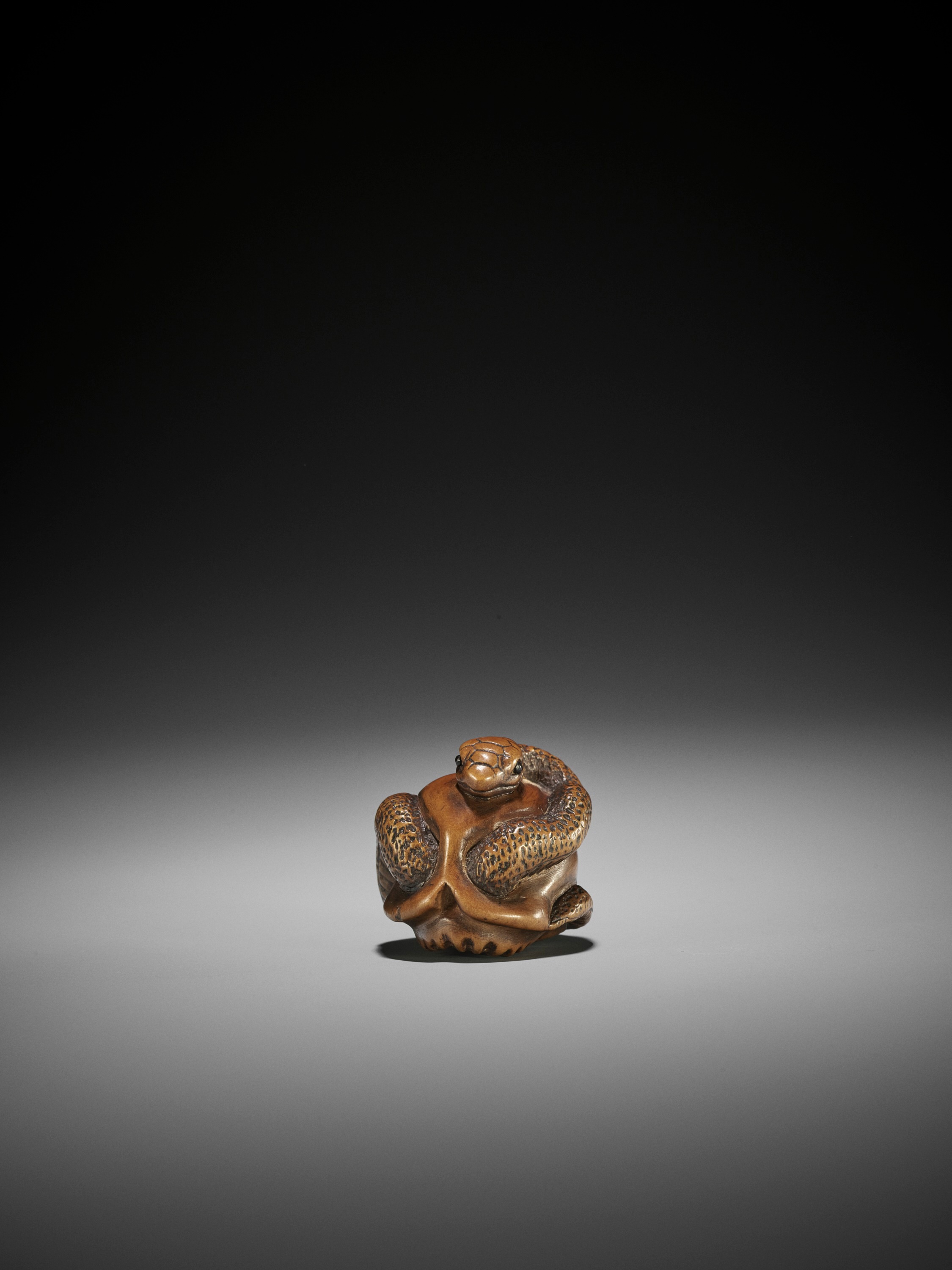 Lot 99 - MASAMITSU: A WOOD NETSUKE OF SNAKE AND SKULL