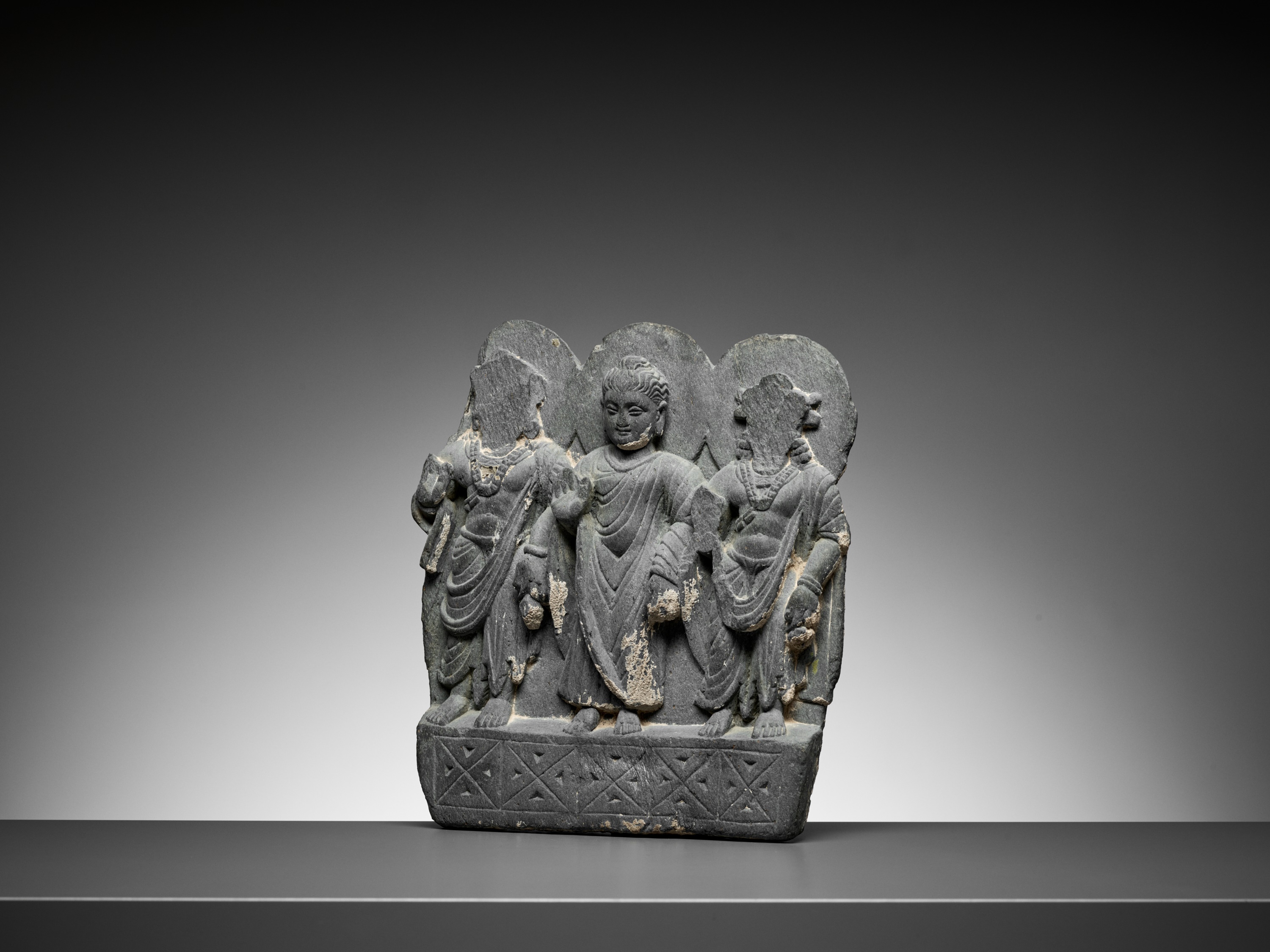 Lot 544 - A GRAY SCHIST RELIEF OF BUDDHA AND TWO