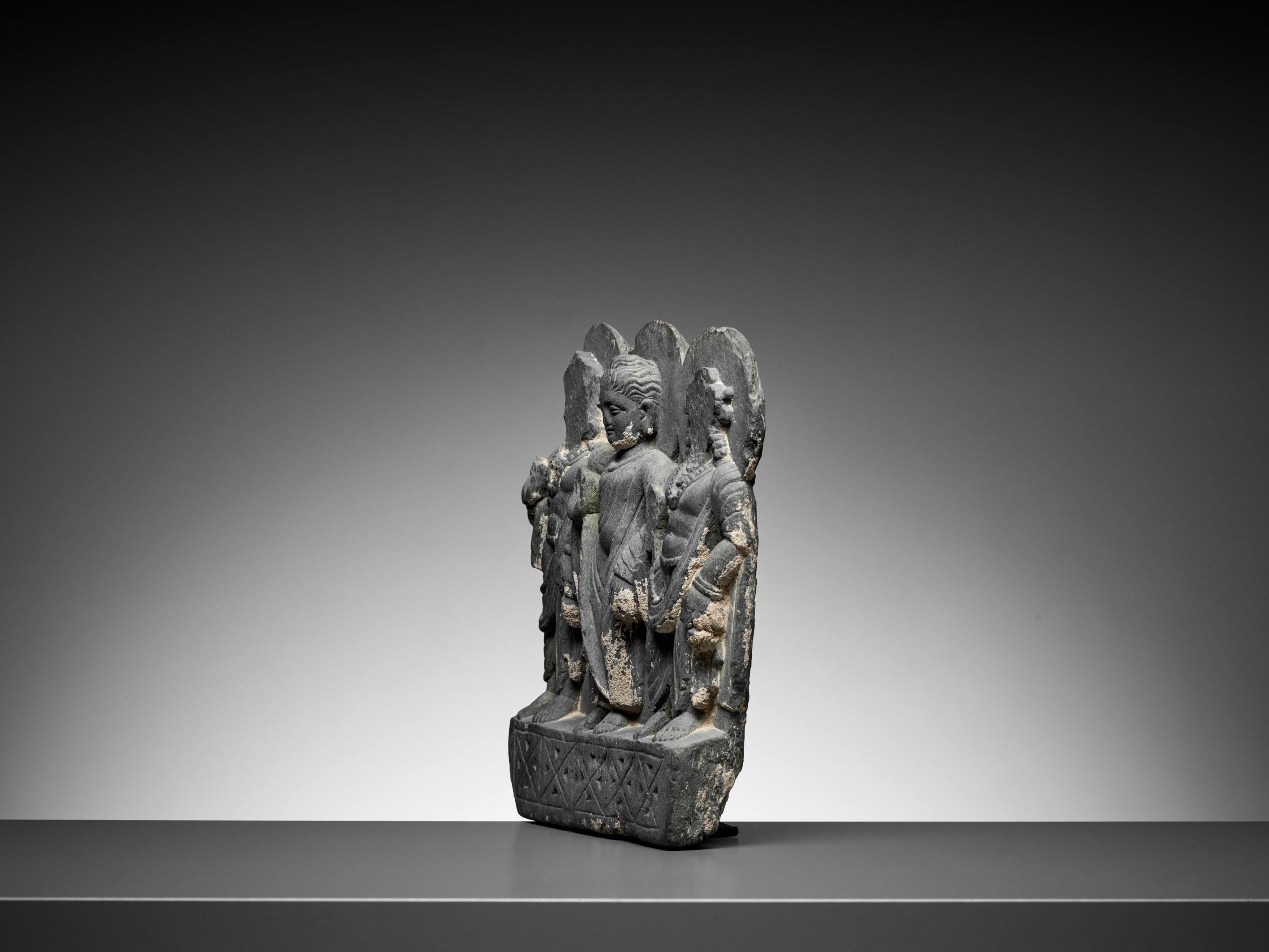 Lot 544 - A GRAY SCHIST RELIEF OF BUDDHA AND TWO