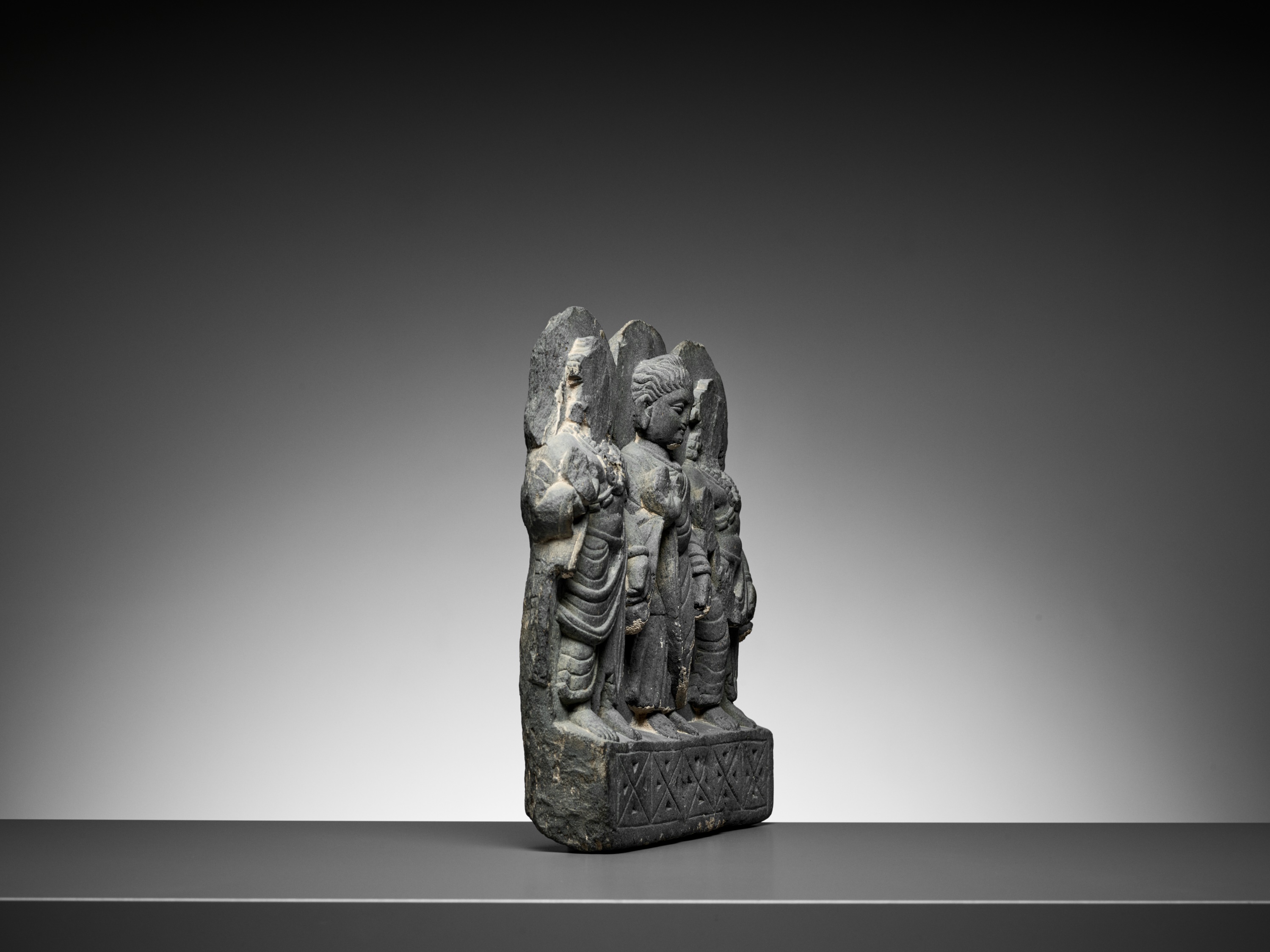 Lot 544 - A GRAY SCHIST RELIEF OF BUDDHA AND TWO