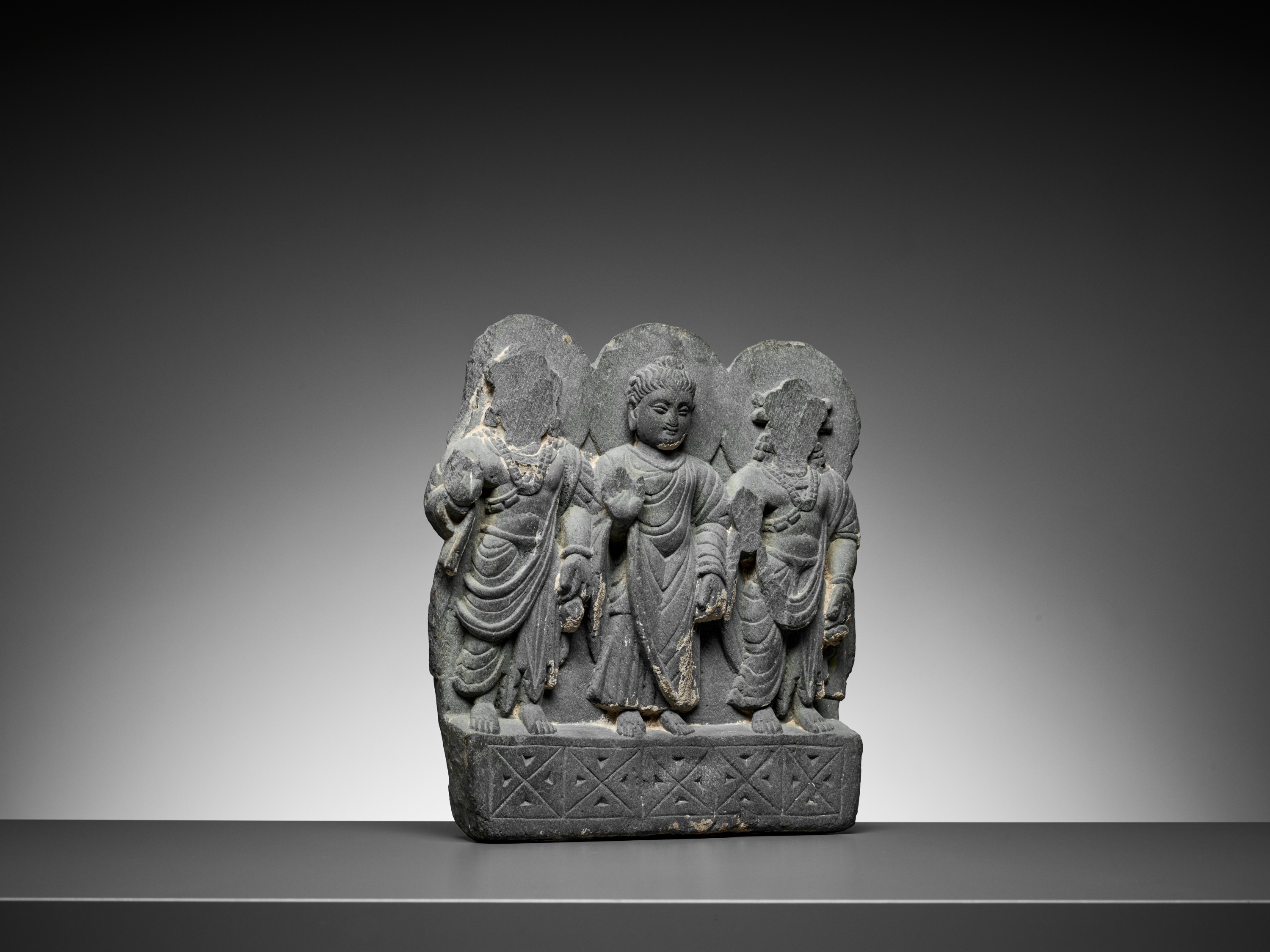 Lot 544 - A GRAY SCHIST RELIEF OF BUDDHA AND TWO