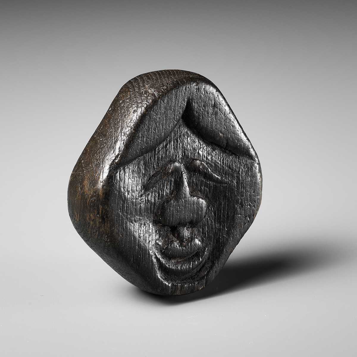 Lot 256 - AN UNUSUAL KIRI (PAULOWNIA) WOOD SHUNGA MASK NETSUKE OF FUKUWARAI TYPE