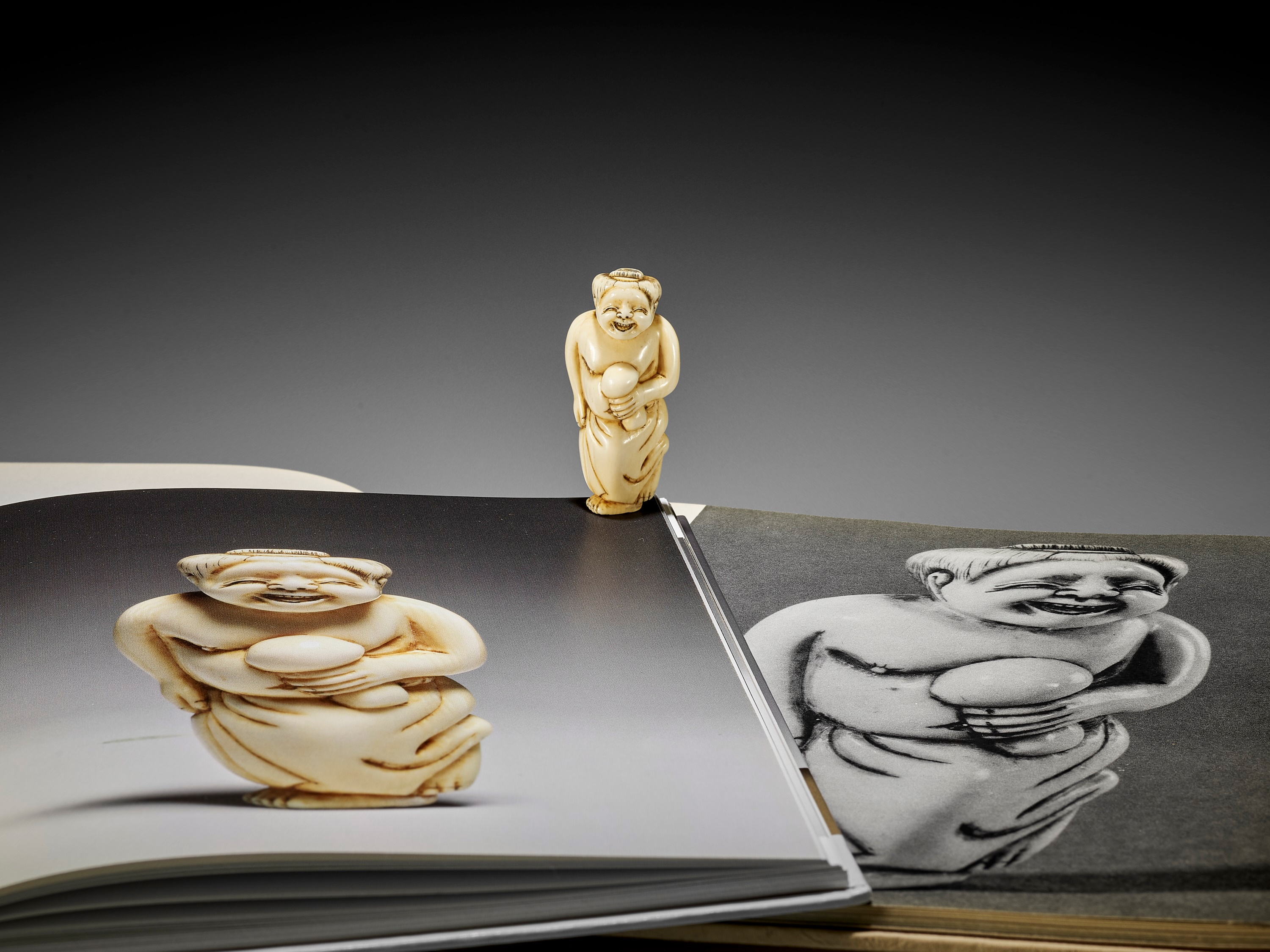 Lot 27 - AN IVORY SHUNGA NETSUKE OF OKAME HOLDING A