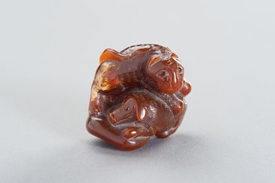 Lot 978 - AN AMBER CARVING OF A TIGER AND DOG