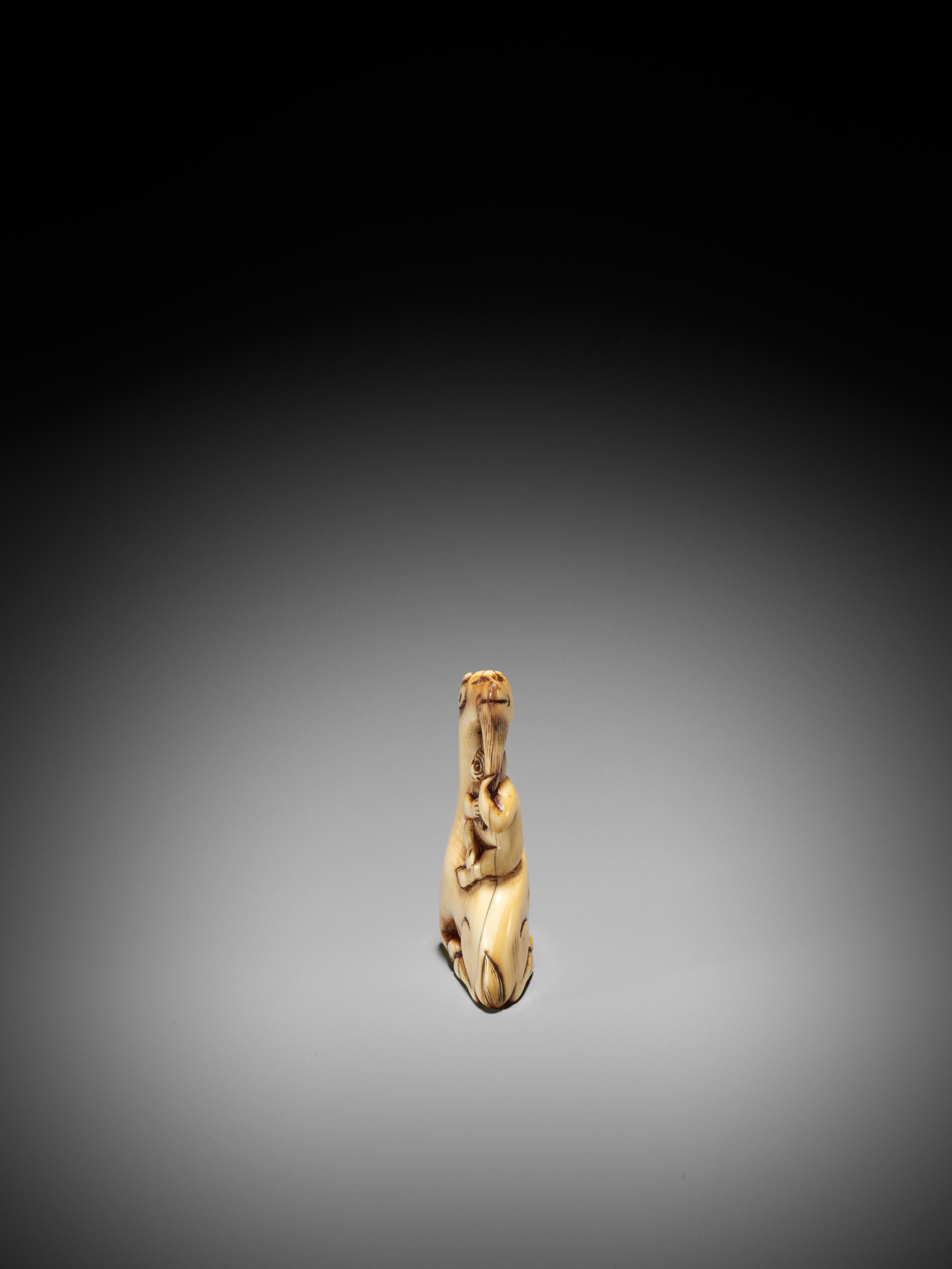Lot 35 - AN IVORY NETSUKE OF A SINIU AND MONKEY