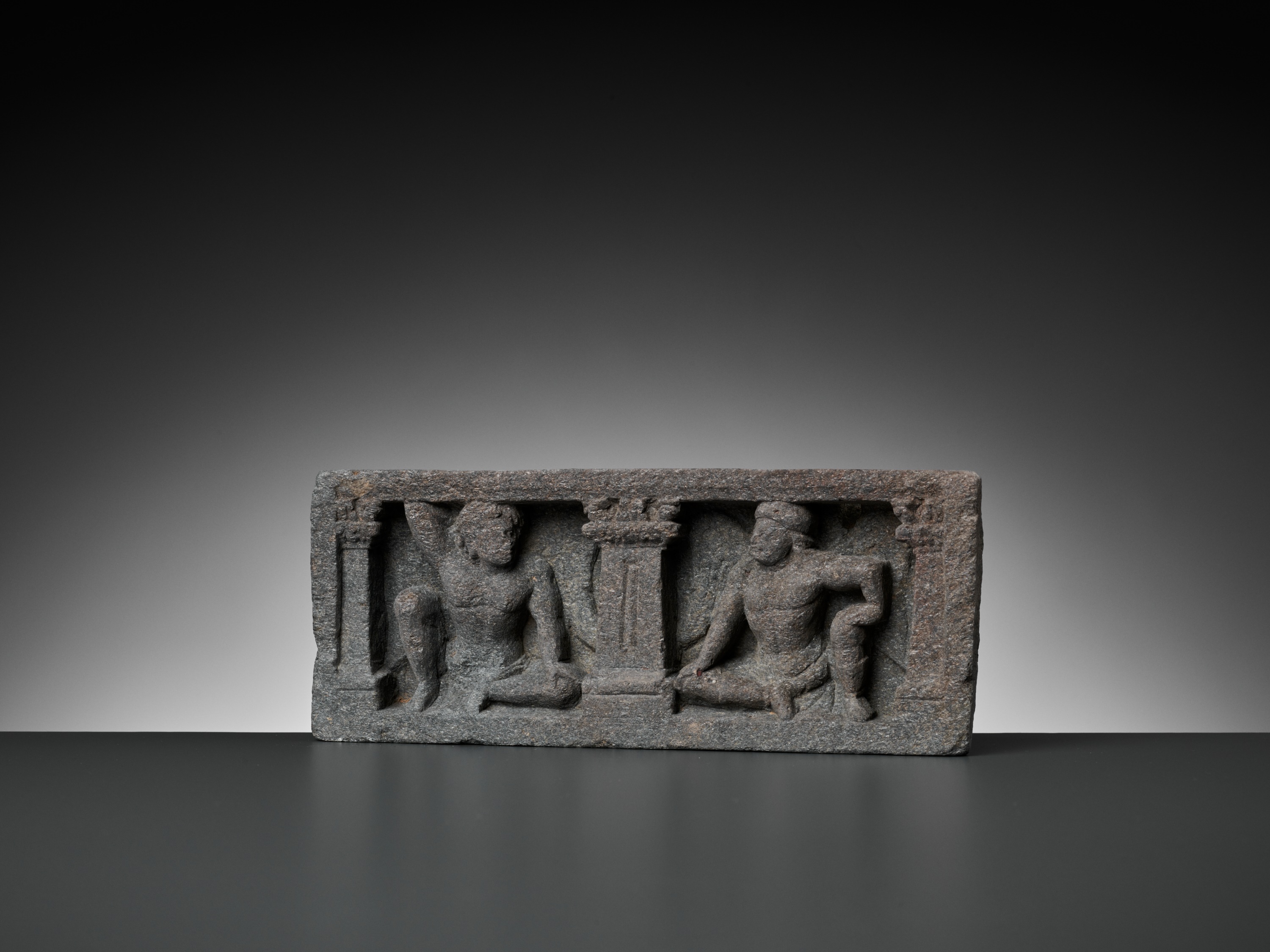 Lot 547 - A GRAY SCHIST RELIEF WITH TWO ATLAS FIGURES,