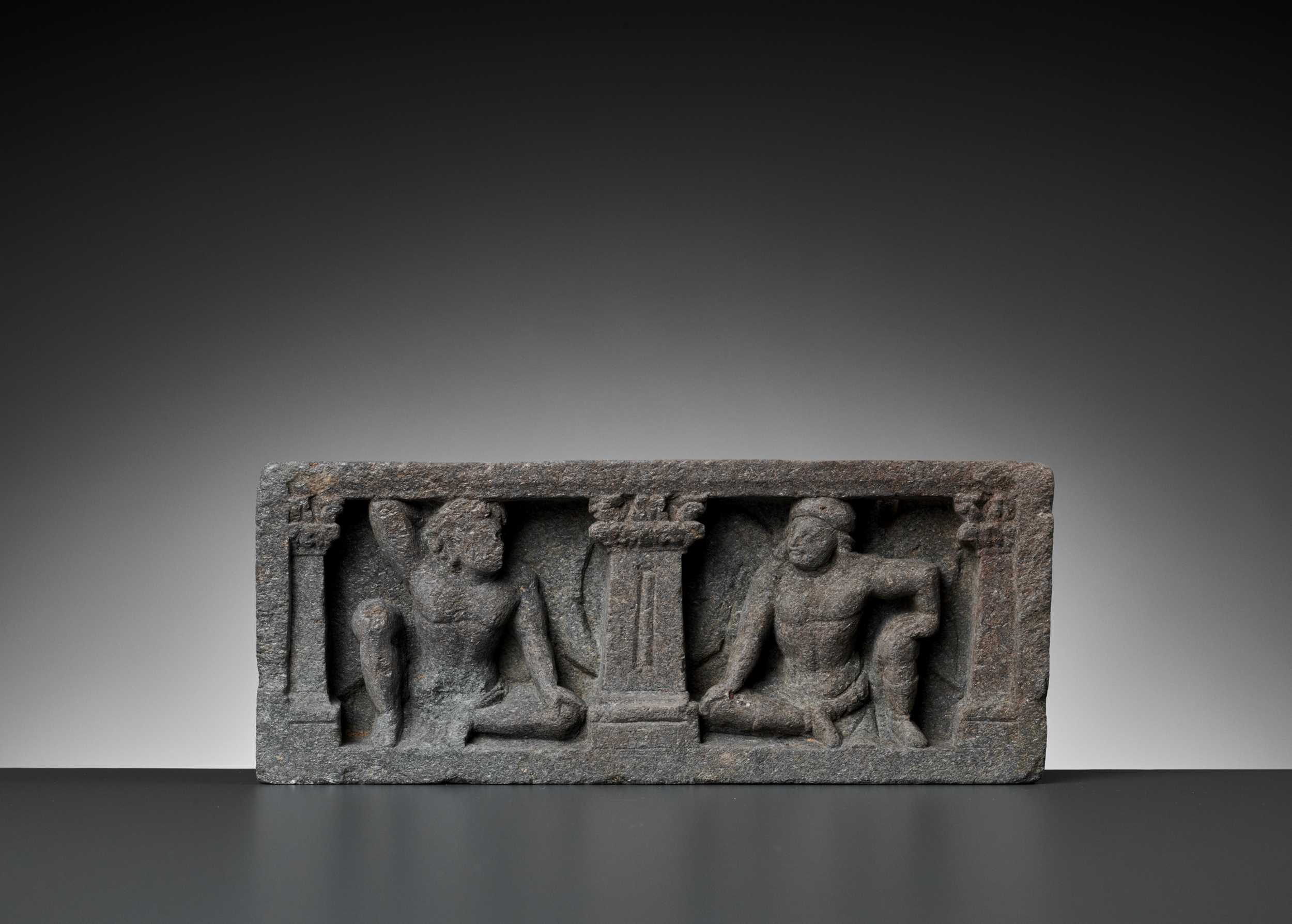Lot 547 - A GRAY SCHIST RELIEF WITH TWO ATLAS FIGURES, GANDHARA