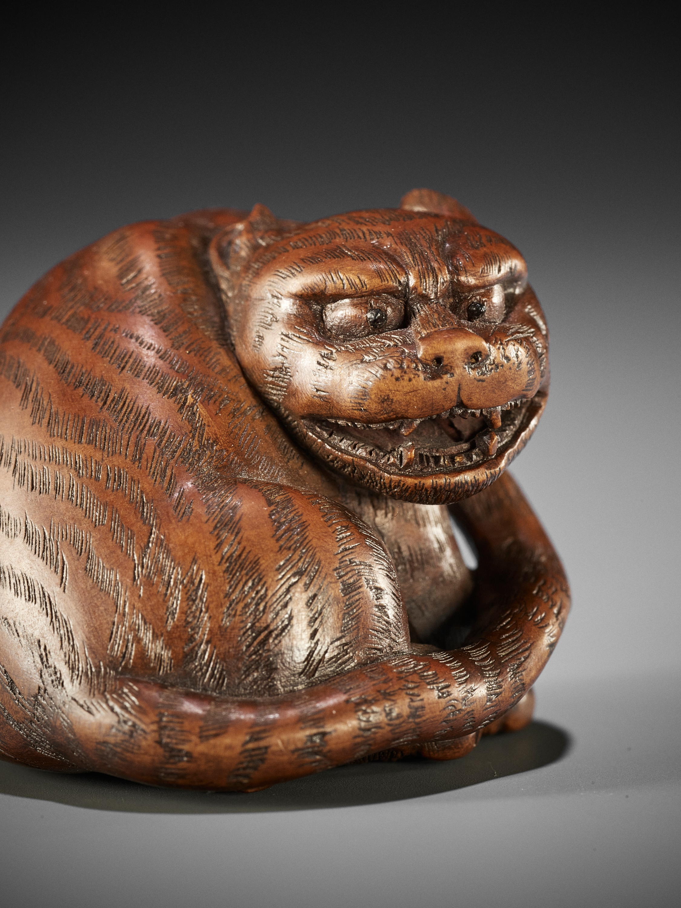 Lot 117 - MASANAO: A SUPERB WOOD NETSUKE OF A TIGER